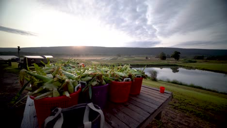 camera pushing in on a tractor and a flatbed loaded with freshly picked corn as the sun rises over the mountain