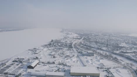 vista aérea de invierno de una ciudad junto a un río congelado