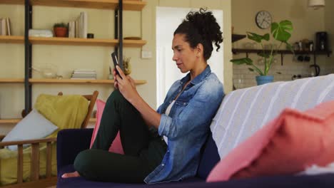 caucasian woman using smartphone, sitting on sofa at home