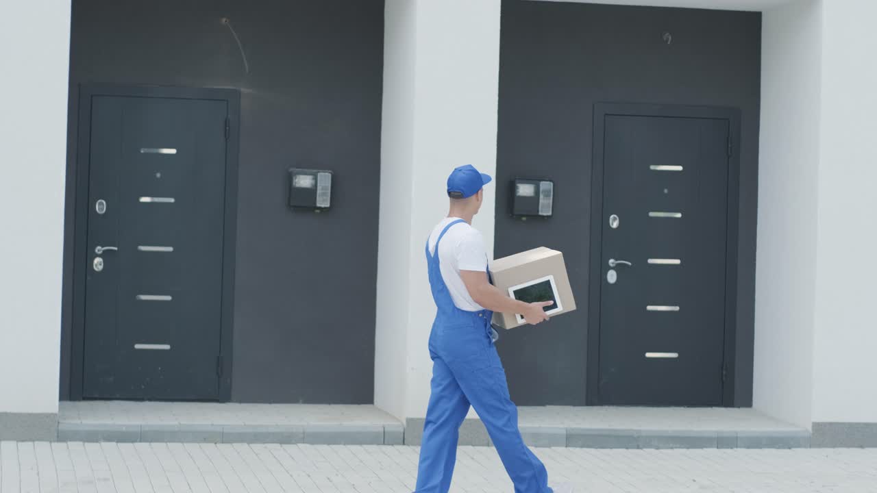 Young courier holding a parcel and tablet walking on the street to deliver a box directly to a customer home.