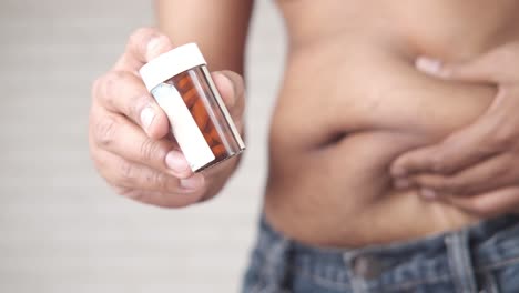 man holding a pill bottle with a large belly