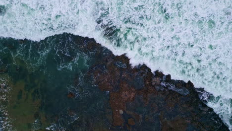 aerial view foamy sea waves crashing huge stones. stormy ocean washing mountain