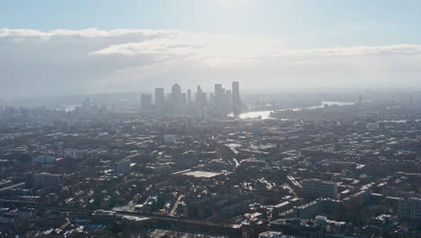 high dolly forward drone shot towards canary wharf london skyscrapers day after snow