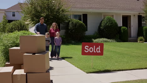 happy family arrives at their new home with a sold sign