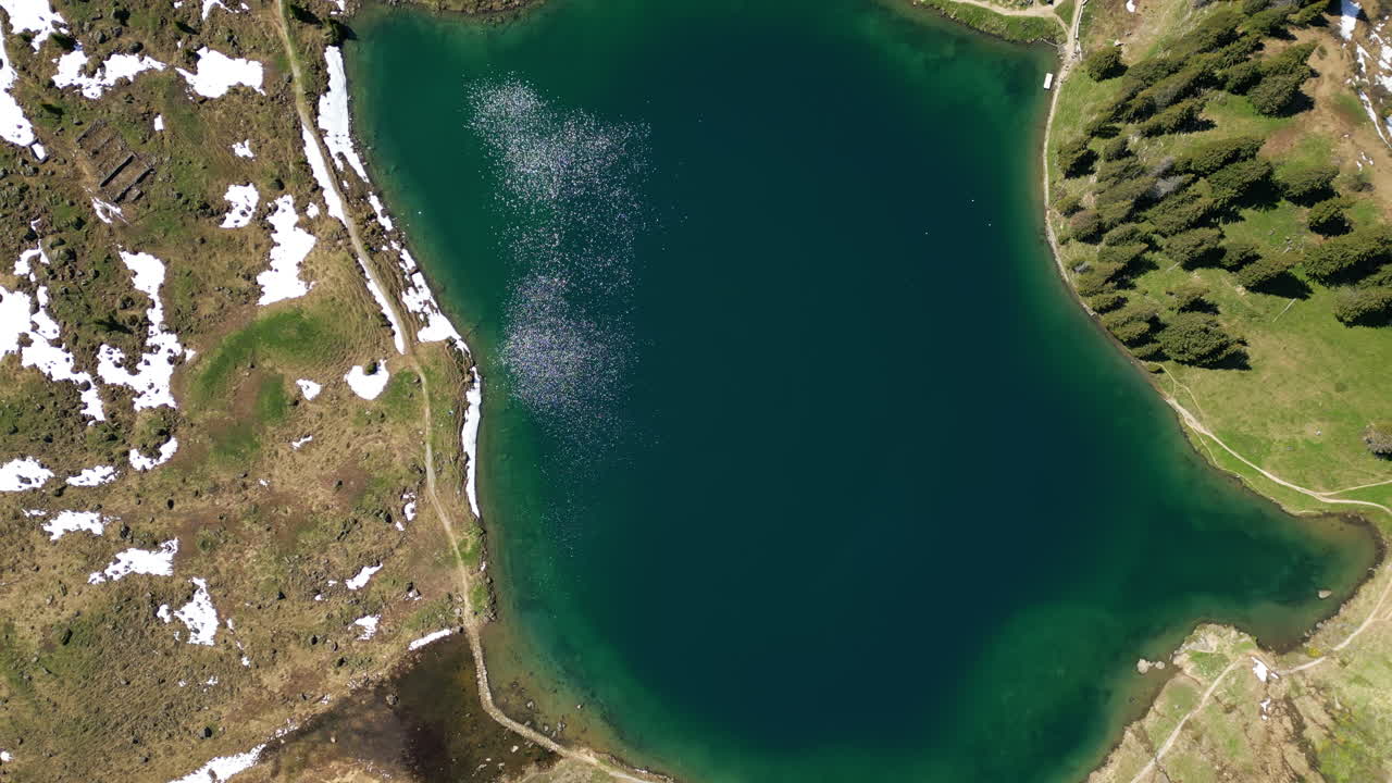 Aerial: Lake Lioson during the day with snow in Ormont-Dessous, near Les Mosses, in the canton of Vaud, Switzerland, top down drone shot