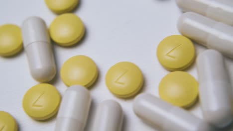 white capsules and yellow pills on clean light background