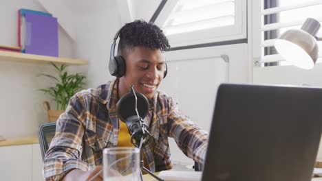Glücklicher-Afroamerikanischer-Männlicher-Teenager,-Der-Laptop-Benutzt-Und-Podcast-Aufnimmt,-Zeitlupe