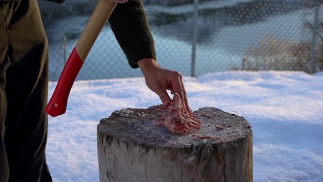 man uses axe to chop deer backbone into pieces for bone broth, slow motion