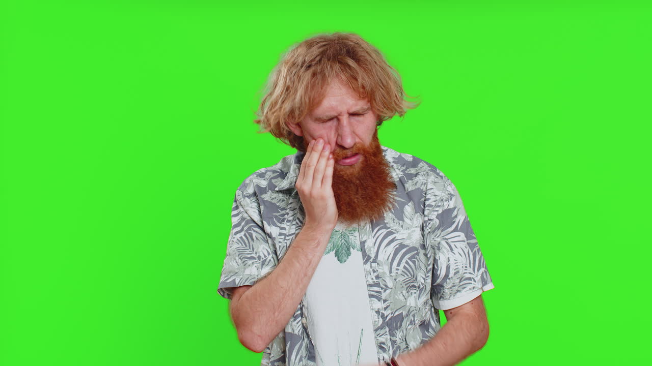 Young man touching cheek, closing eyes with expression of terrible suffer from painful toothache