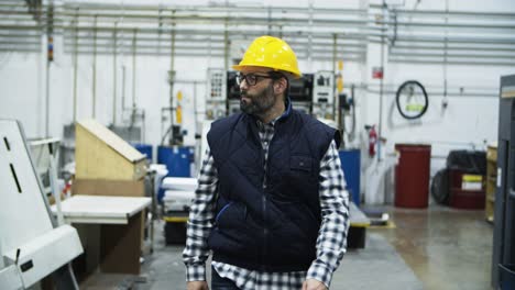 front view of serious mature technician walking at plant