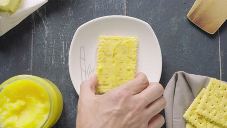 man's hand takes a soda cracker on a plate