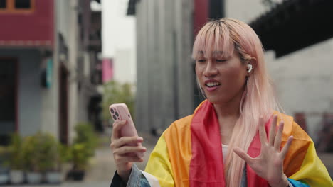 transgender person using smartphone for video call, rainbow flag