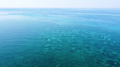 Aerial-drone-flight-across-coral-reefs-and-stunning-blue-ocean-with-crystal-clear-water-in-the-Coral-Triangle-in-a-remote-tropical-destination