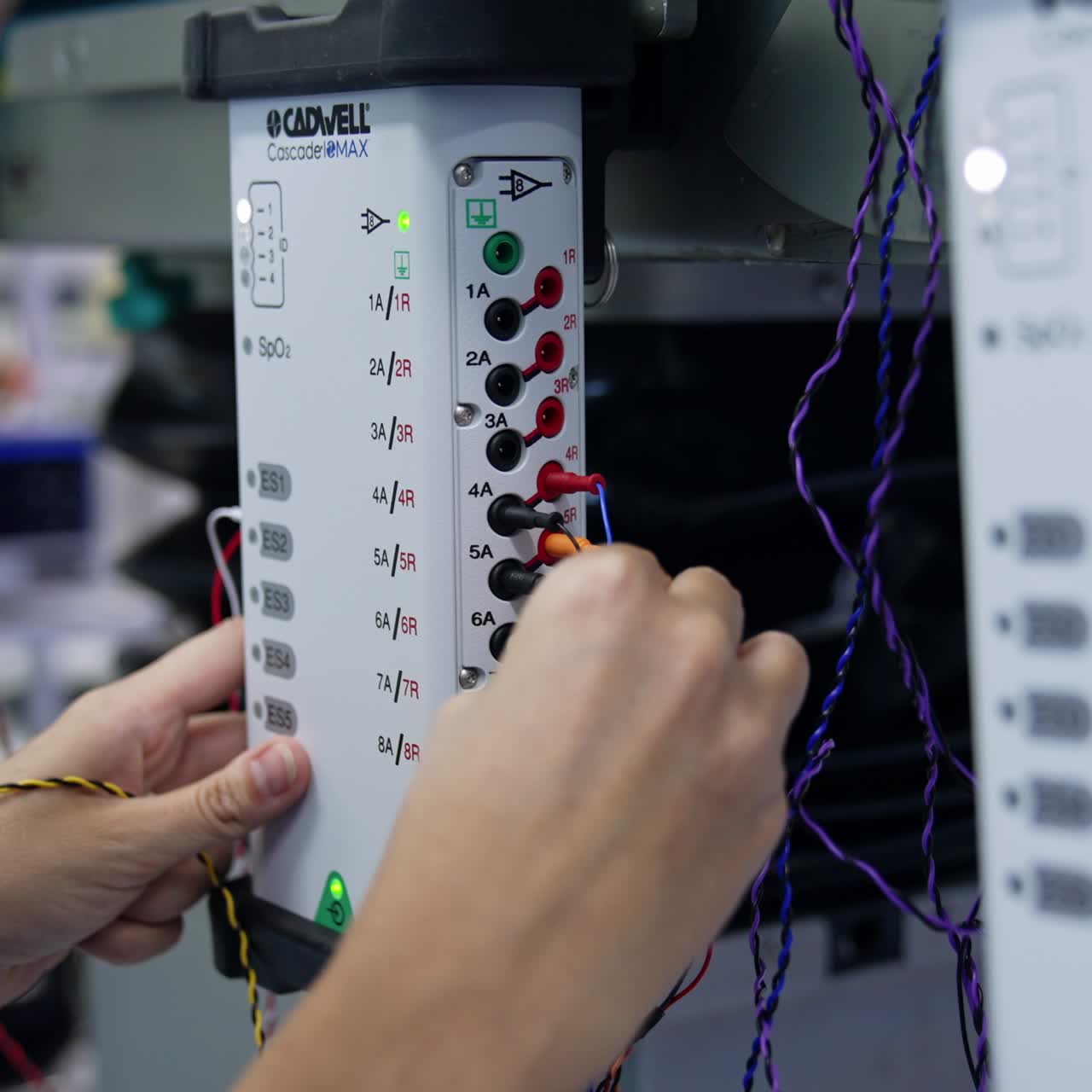 Female hands connect the wires to the apparatus. Preparation of equipment for neuromonitoring. Close up