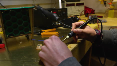 hombre trabajando en una placa de circuito con un soldador, de cerca, filmado en r3d