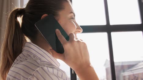 Elderly-woman-in-orange-sweater-smiles-while-video-calling-on-smartphone..Elderly-woman-in-orange-sweater-smiles-while-video-calling-on-smartphone.-Happy-female-talking-online-with-loved-ones.-She-stands-outside-with-earphones,-enjoying-conversation-in-green-park-setting