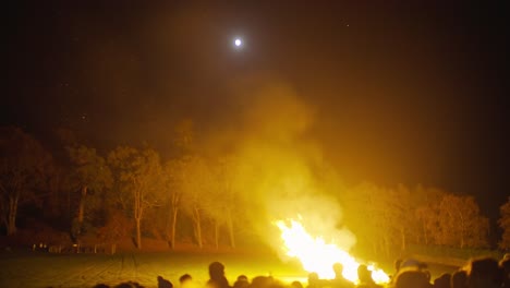 Night-Time-Large-Campfire-Outside-With-Sillhoute-Of-Crowds