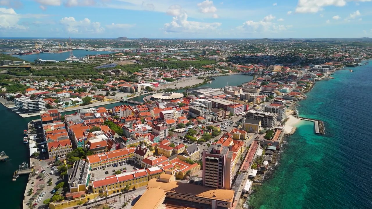 Luftnedstigning over Punda-distriktet i Willemstad Curacao avslører nederlandske koloniale oransje tak, St. Anna-bukten, cruisehavnen og turkis karibisk kystlinje.