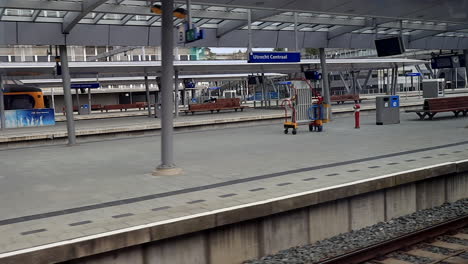 Empty-Platform-In-Utrecht-Central-Railway-Station-As-Seen-From-A-Moving-High-speed-Train---Coronavirus-Lockdown-In-Netherlands---panning-shot