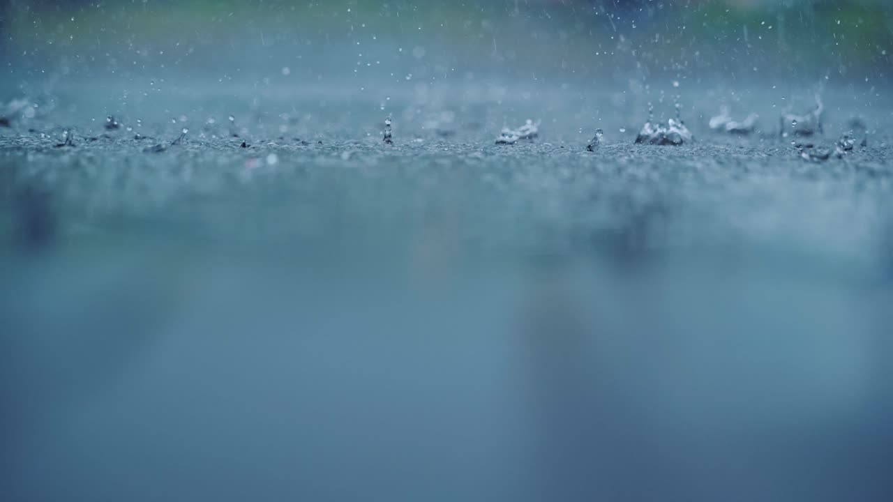 Slow motion rain splashes in upper third while blurred surface adds depth calm