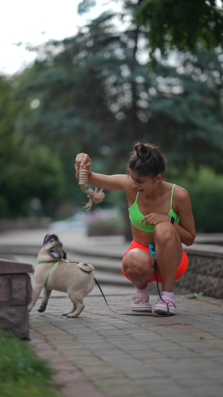 mujer jugando con un pug en un parque