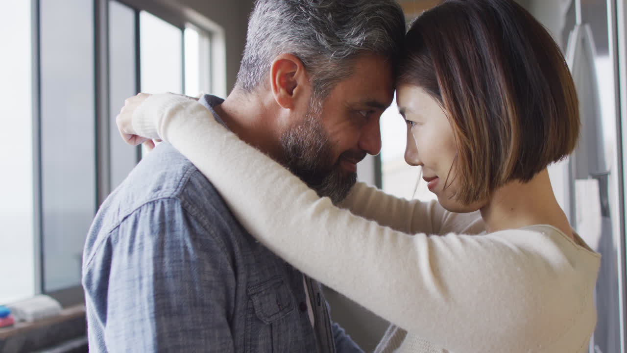 pareja feliz tocando las frentes y bailando juntos en la cocina