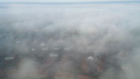 static drone footage of fast rolling fog with houses underneath