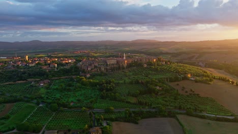 Aerial-at-sunset-over-the-Tuscany-landscape-with-the-city-of-Pienza-at-the-top-of-the-hill,-Province-of-Siena,-Italy
