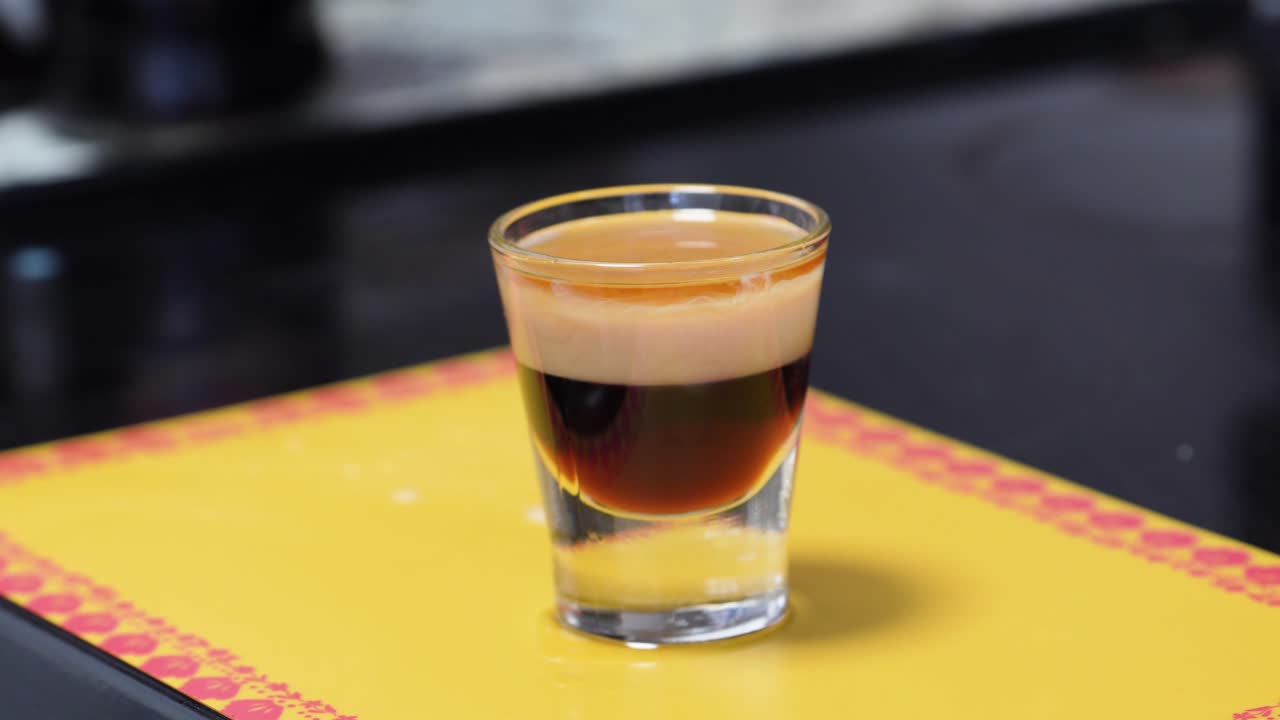 Versare Cointreau sul retro di un cucchiaio freddo. Tecnica di stratificazione dello shot B-52. Primo piano