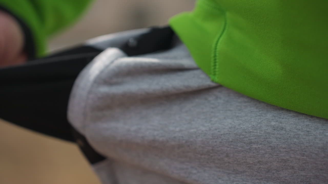 손이 장치를 가리고 있어요. 걷는 동안 스마트폰을 옷 주머니에 넣는 손을 클로즈업하여 포착하고, 편안하게 걸을 때 츄리닝 바지 주머니에 장치를 몰래 넣는 손을 자세히 클로즈업해요.