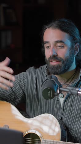 bearded musician playing acoustic guitar and singing into microphone