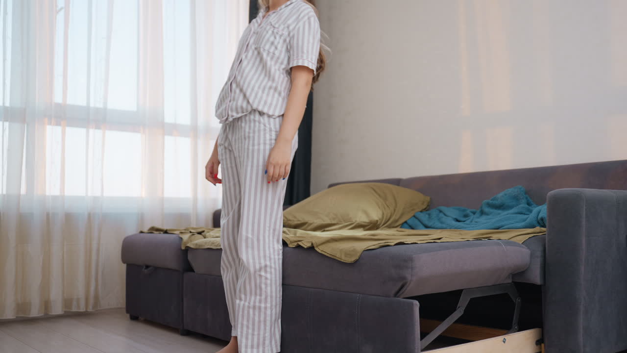 Caucasian Woman Sitting On Bed Then Reclining, Striped Pajamas, Slow Stretch Then Legs Up, Nurse Trainee Taking Breather After Early Shift, Soft Curtain Light And Calm Bedroom Ambience