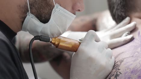tattoo artist applying tattoo on client's back