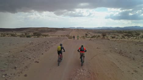 aerial footage of a group of bicycle riders riding on bike trails in the desert