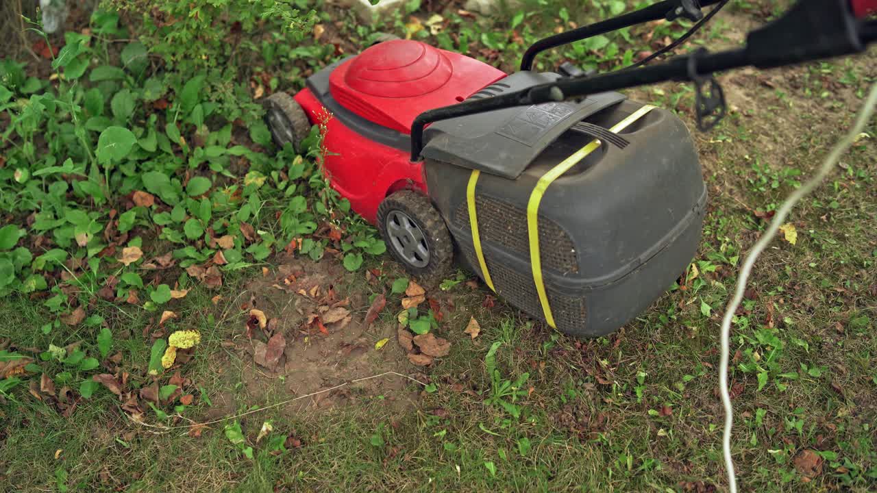 Red lawn mower cutting grass. Landscaper cutting grass with lawn mower