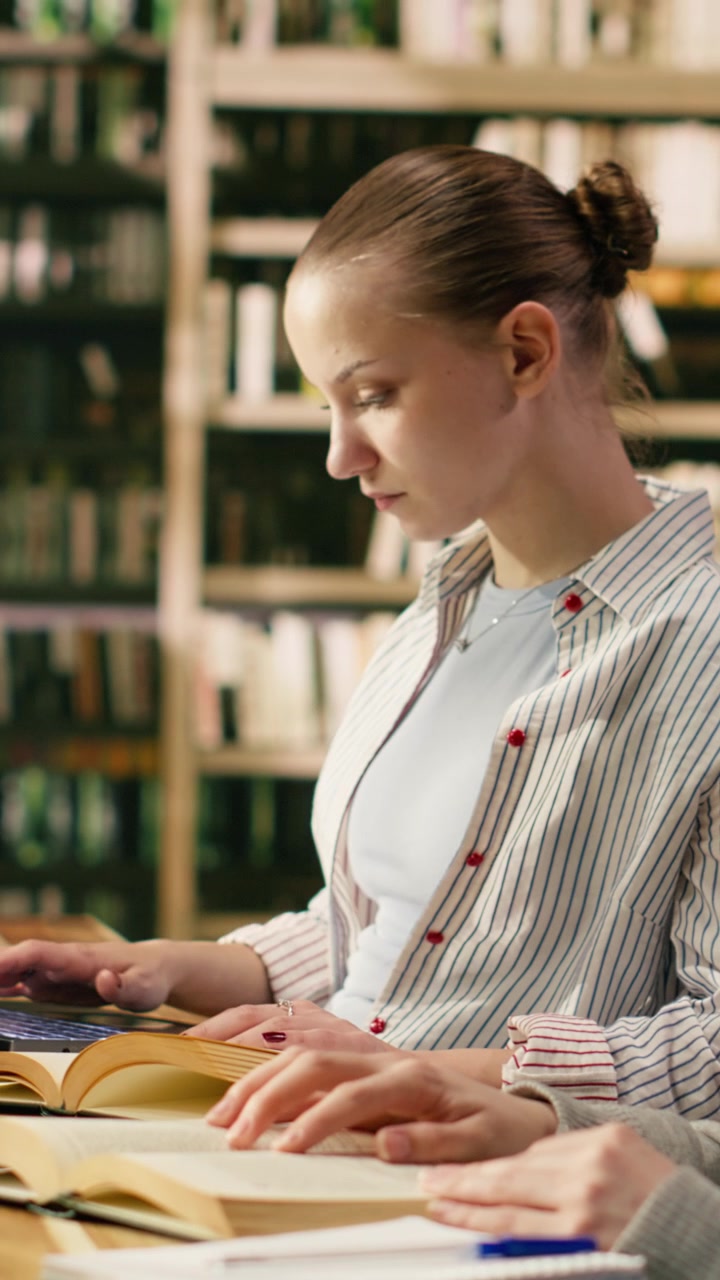Vertikal video: Studenter sitter på biblioteket, leser bøker og bruker bærbar PC.