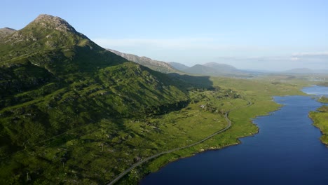 Twelve Bens Mountains, Recess, Connemara, County Galway, Ireland, July 2021. Drone slowly pushes east over Ballynahinch Lake and Garraun mountain complex with Ballinafad and Maam in the distance