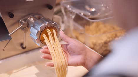 El-Cocinero-Masculino-Acompaña-Las-Largas-Hebras-De-Espagueti-De-La-Máquina-De-Pasta