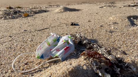 Kids-disposable-face-mask-discarded-on-the-sand