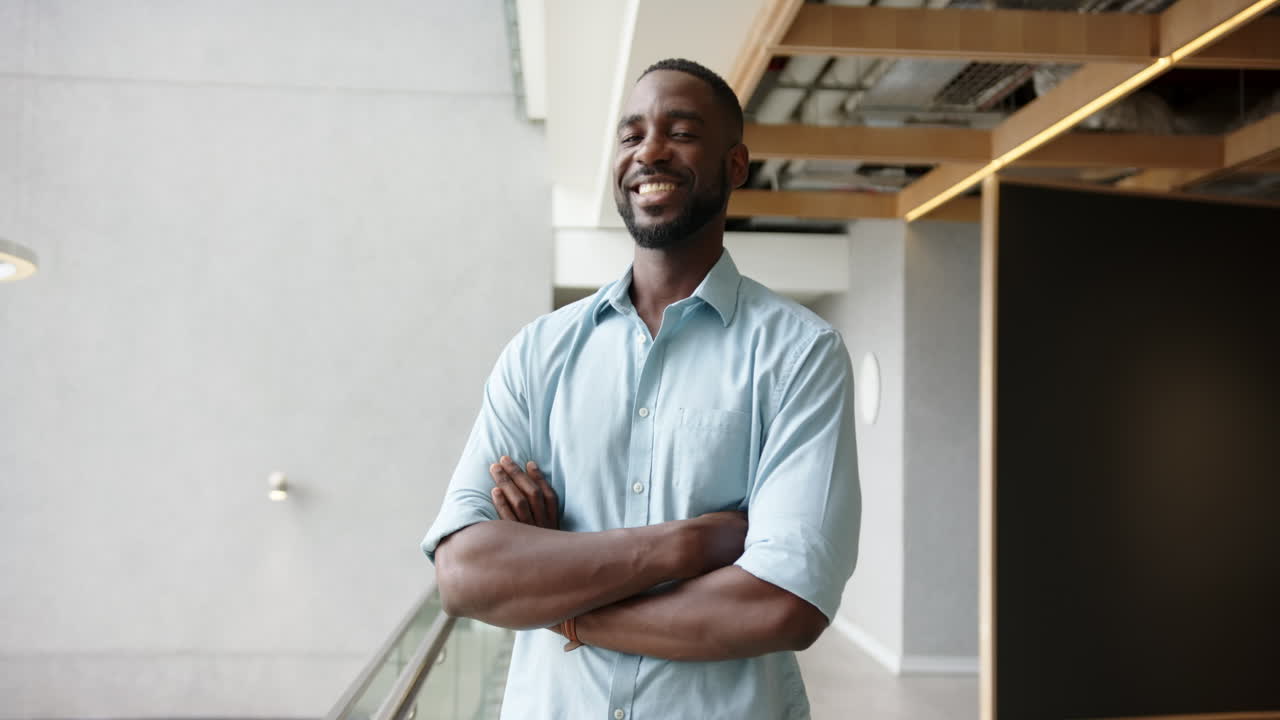 Smiling African American man in office environment standing with arms crossed, looking confident
