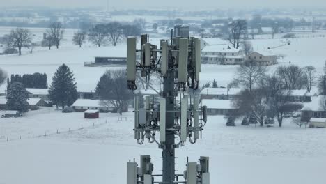 aerial view of a snow-covered rural landscape with a prominent cellular tower in the foreground, highlighting the blend of technology and nature