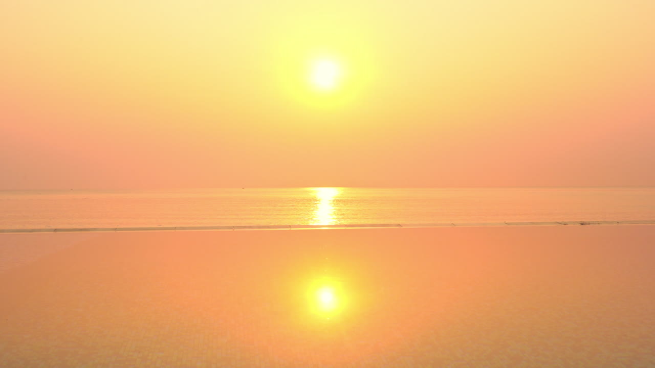 바다와 인피니티 풀에 반사되는 놀라운 밝은 황금빛 태양