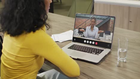 Mujer-Birracial-Usando-Una-Computadora-Portátil-Para-Videollamada,-Con-Un-Colega-De-Negocios-En-La-Pantalla