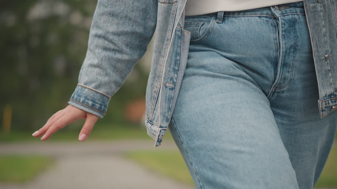 Camminando in abbigliamento di jeans suburbano. Persona che cammina casualmente in una tranquilla strada di quartiere. Qualcuno che passeggia tranquillamente lungo un viale suburbano pacifico vestito con abiti di jeans testurizzati