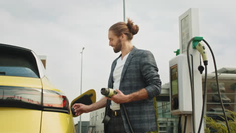 man charging electric vehicle at a charging station