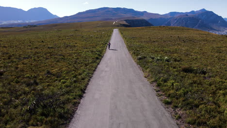 Cyclist-on-tarred-mountain-road-through-fynbos-of-Fernkloof-Nature-Reserve