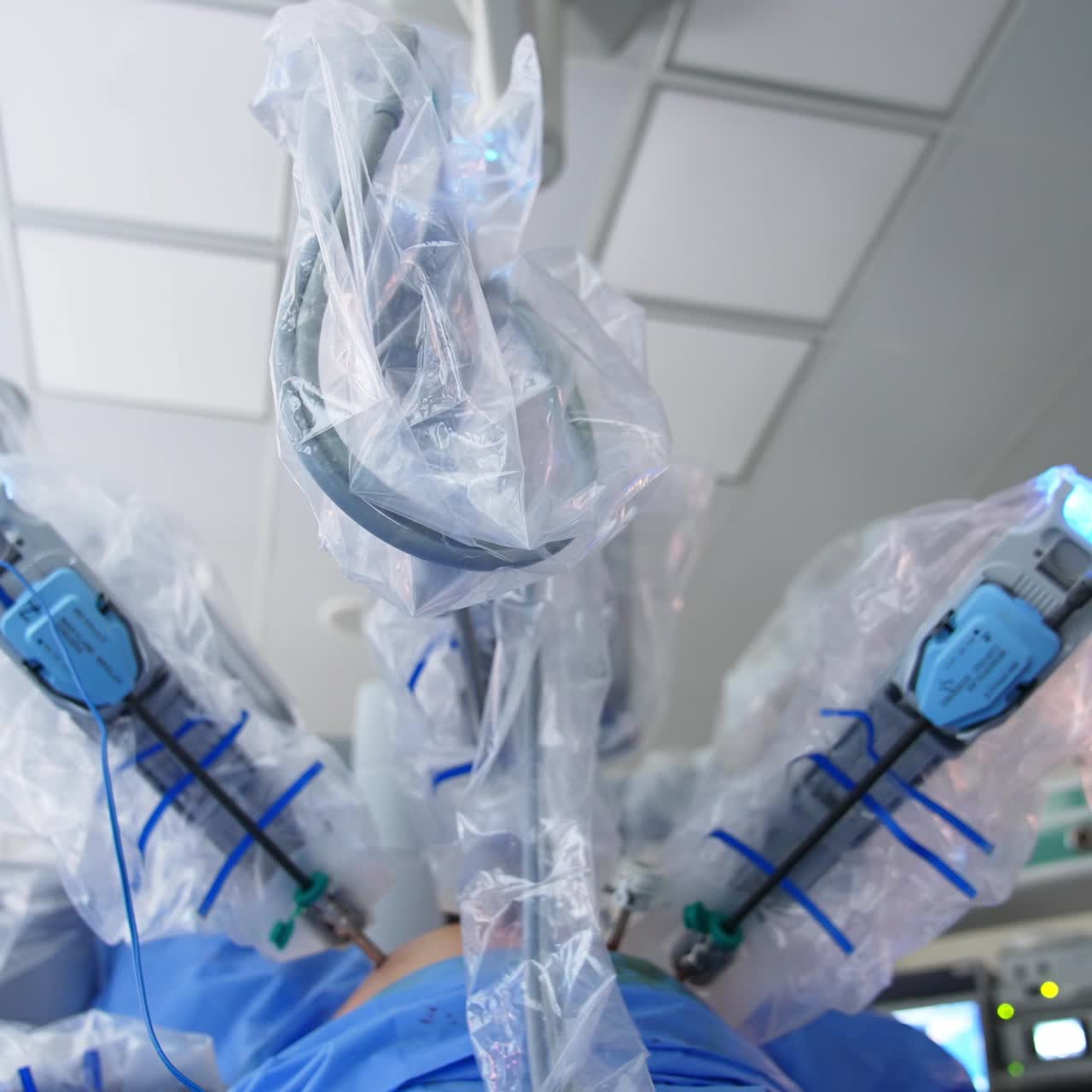 Moving robotic arms in sterile plastic cover during surgery. Low angle view on the futuristic equipment at work. Close up. Blurred backdrop