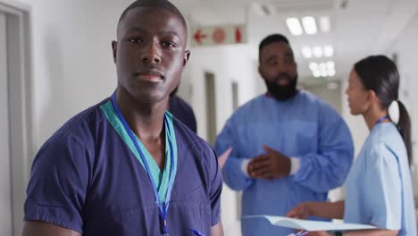 video portrait of smiling african american male medical worker in busy hospital corridor