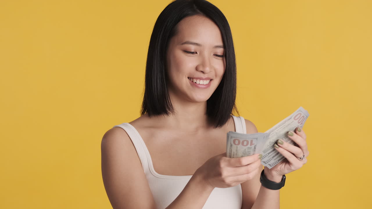 Asian woman counting money on camera.