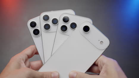 hands holding multiple white smartphones